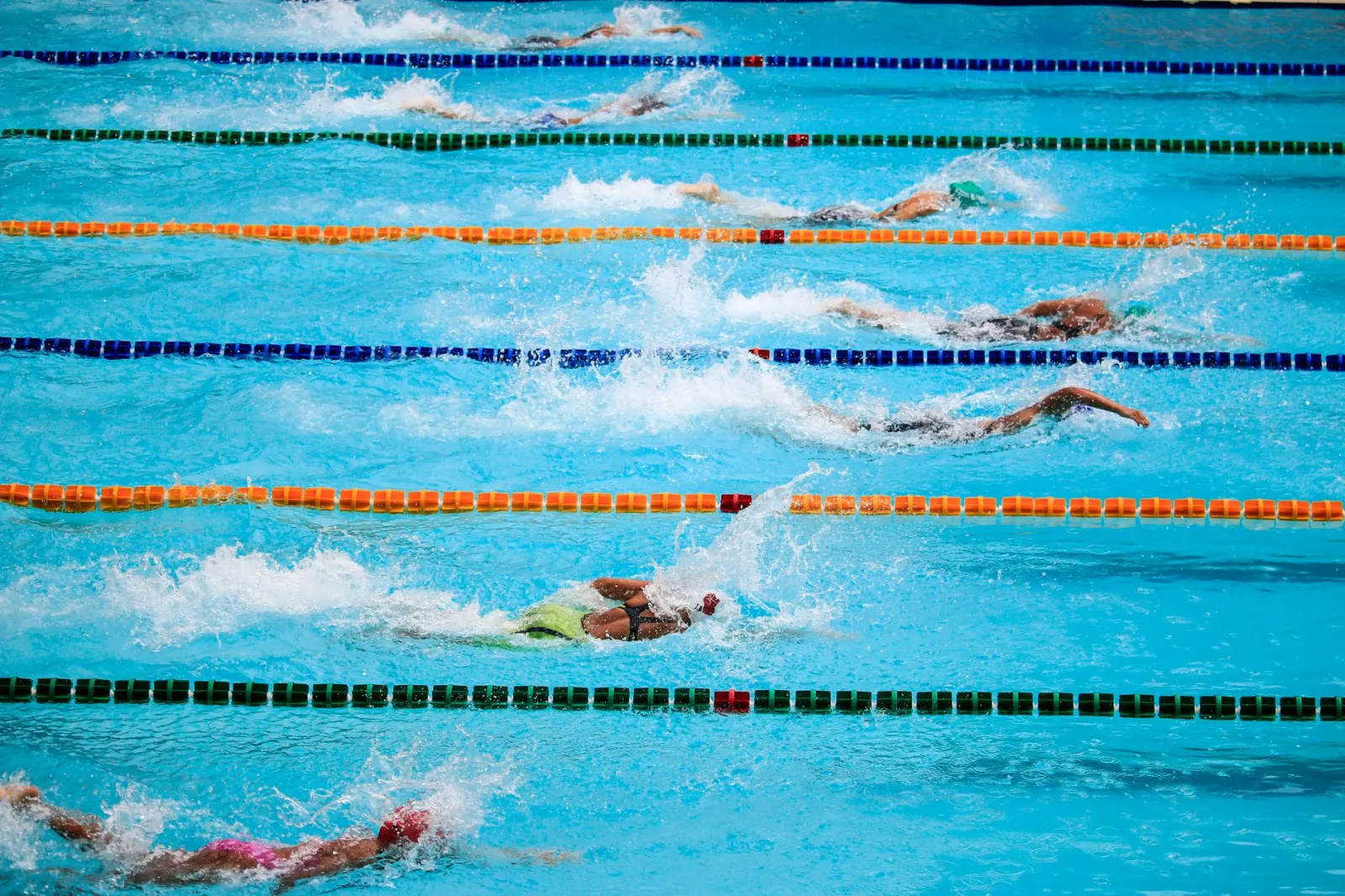 Zwemmers strijden in een buitenzwembadwedstrijd en tonen atletisch vermogen en sportiviteit.